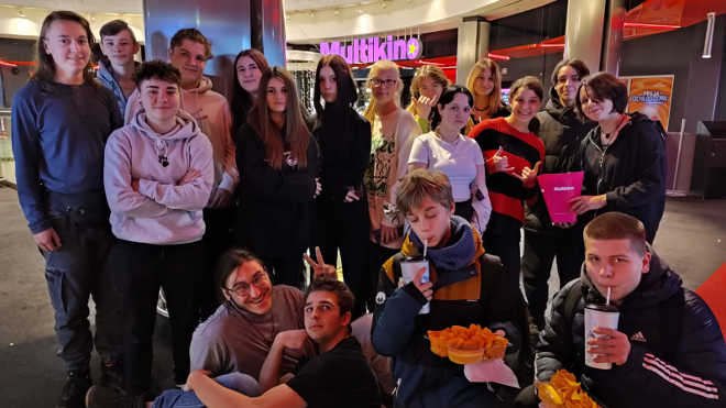 grupa uczniów czekająca na film przed kinem