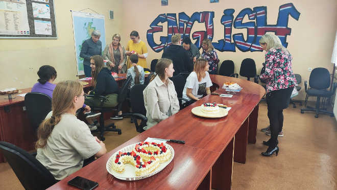grupa uczniów i nauczycieli oglądających konkursowe ciasta
