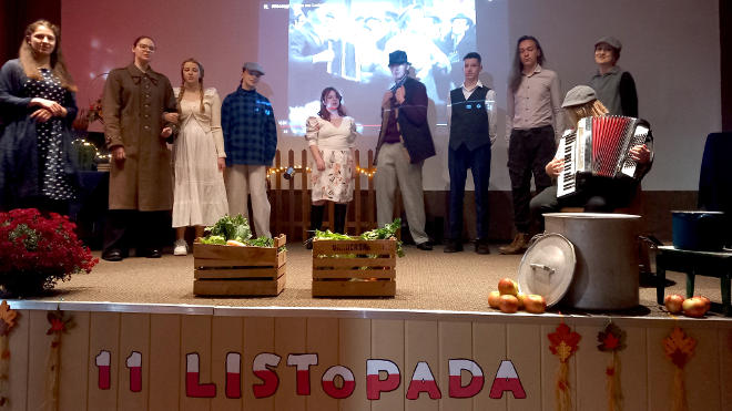 uczniowie w roli mieszkańców Lwowa, na pierwszym planie skrzynki w warzywami