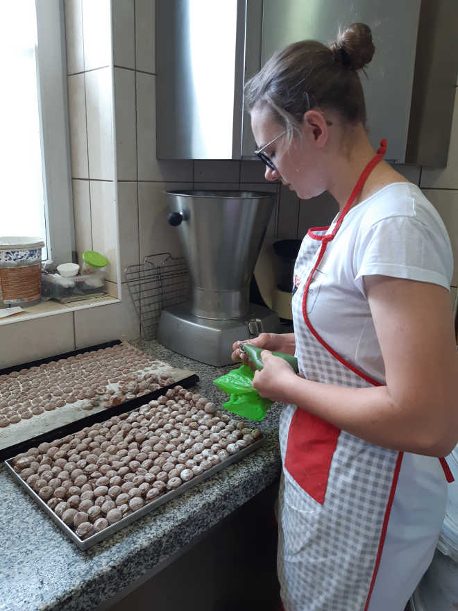 uczennica przygotowuje małe ciasteczka, łącząc małe korpusiki kremem