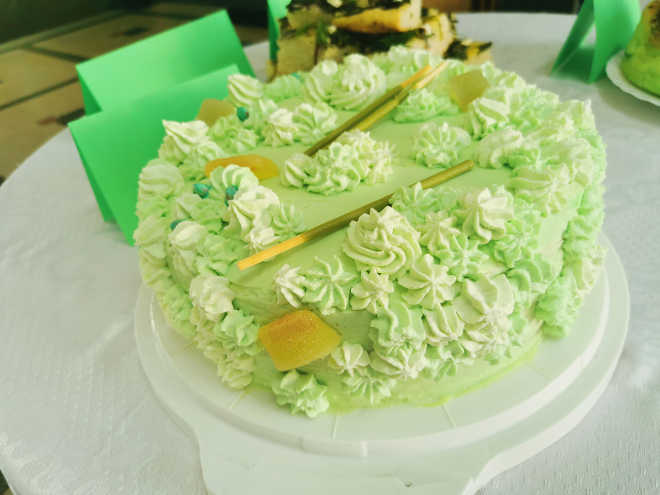 tort wykończony zielonym kremem i białymi rozetkami