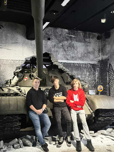 chłopcy stojący przed czołgiem