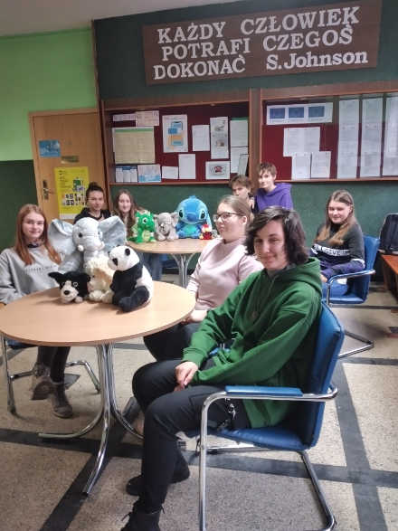 grupa uczniów z zabawkami pluszowymi w czasie przerwy siedząca przy stoliku